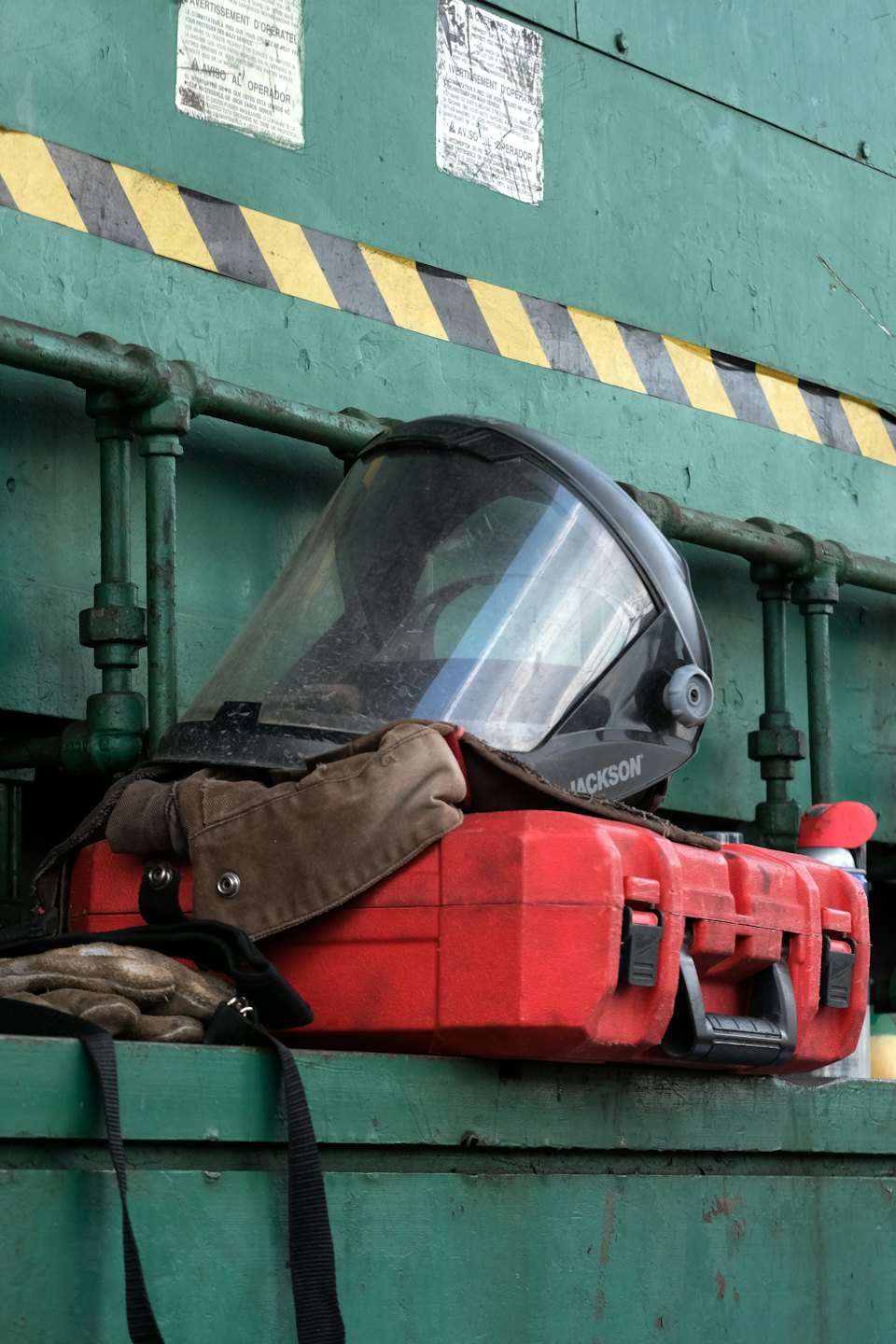 Safety helmet and work gloves resting on a red toolbox.