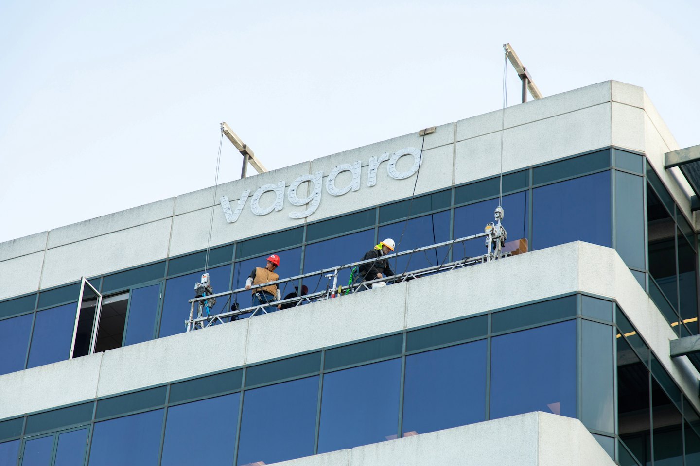 Two construction workers on a scaffold maintenance the building facade.